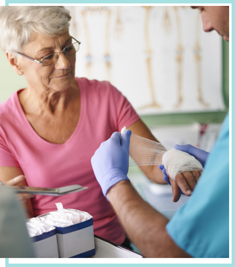 Male physician wrapping an elderly woman's arm wound